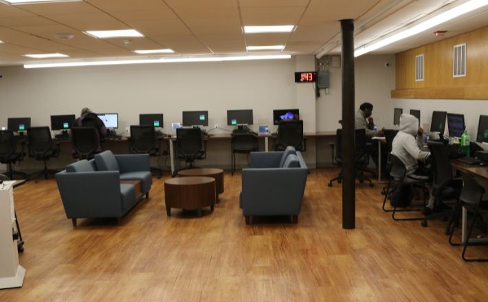 Computer lab full of chairs, computers and two couches