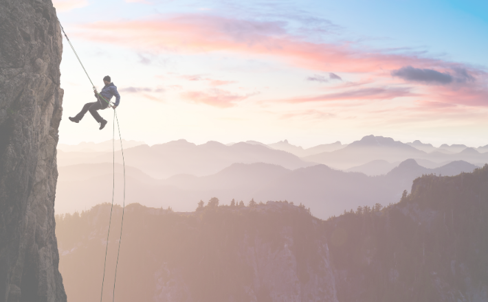 Person repelling down the side of a mountain