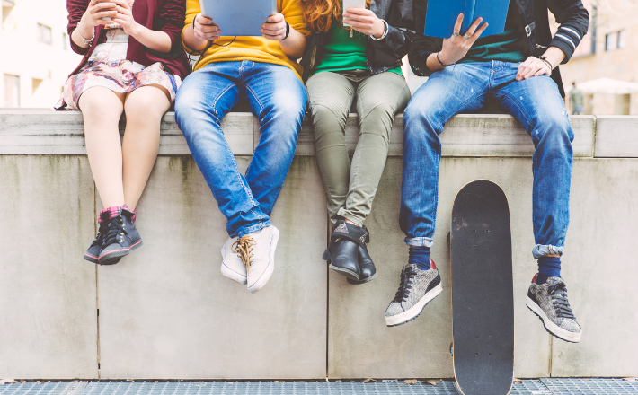 A group of teens sitting on a concrete wall.