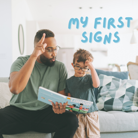 A father and a child reading a book while communicating in sign language with each other.