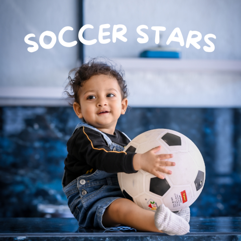 A toddler sitting while holding a soccer ball.