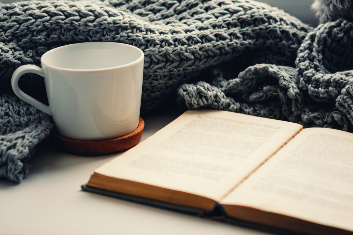 book and cup with blue afghan behind them