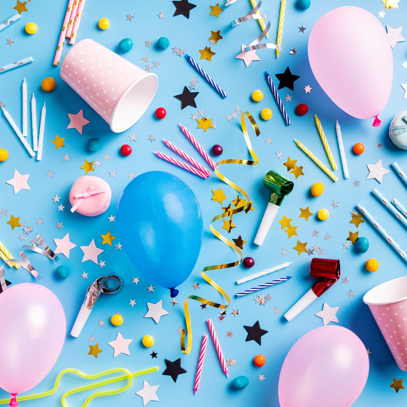 A variety of birthday party supplies, such as balloons, candles, and cups.