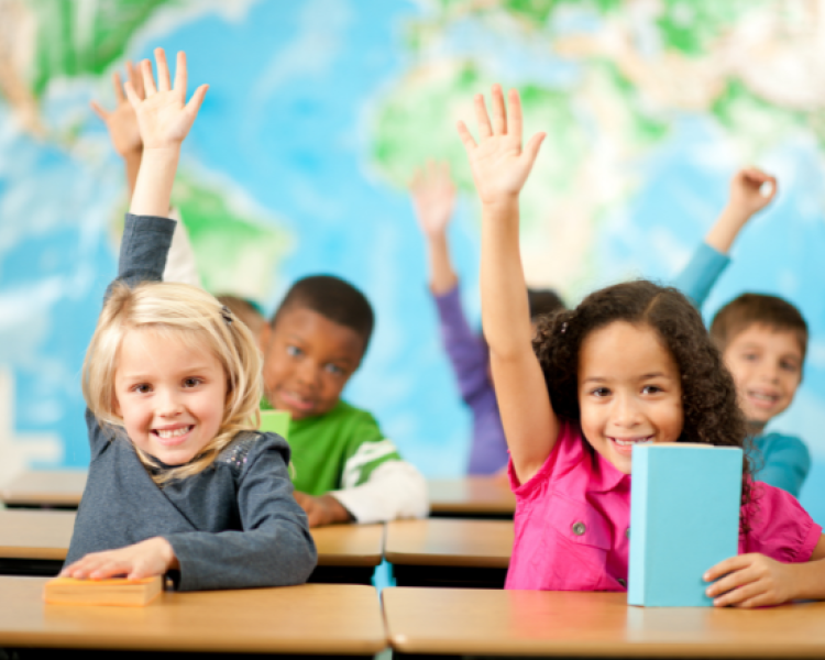 A classroom of children raising their hands