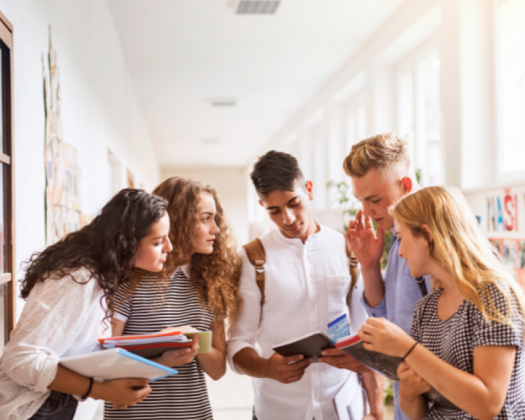 Group of five teens huddled together with books