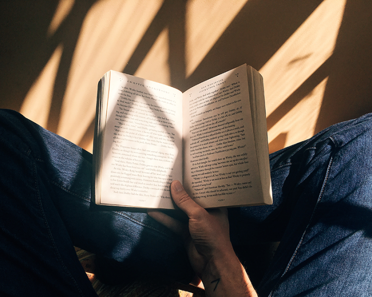 Person sitting cross-legged with an open book in lap